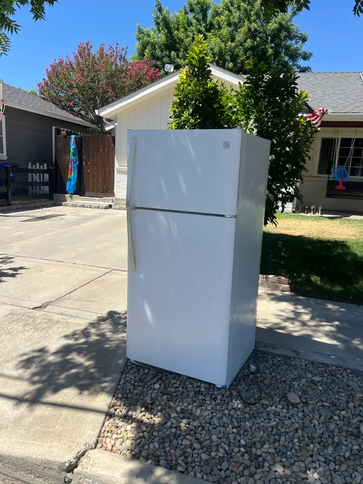 Old white refrigerator on a Fresno driveway ready for pickup